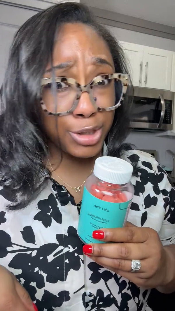 Customer holding a bottle of The Androgen Reset in her kitchen